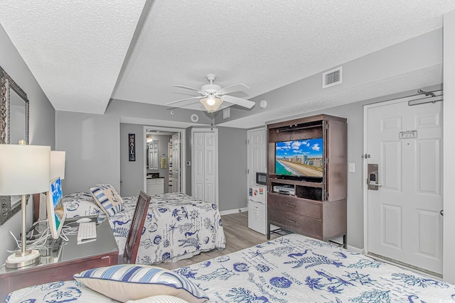 bedroom featuring a textured ceiling, ceiling fan, wood finished floors, and visible vents