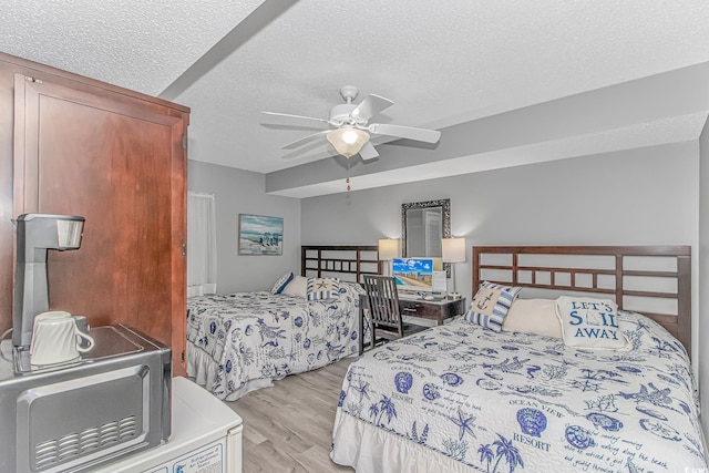 bedroom with a ceiling fan, a textured ceiling, and light wood finished floors