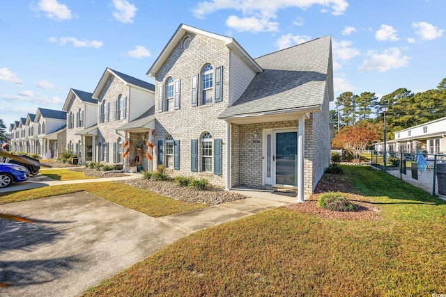 view of home's exterior with brick siding, a shingled roof, fence, a lawn, and a residential view