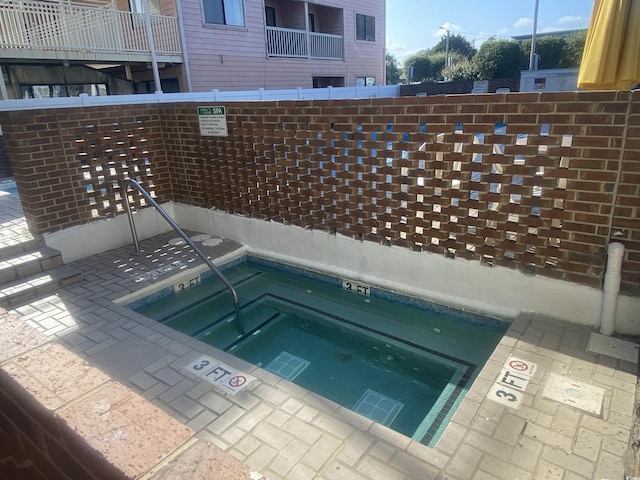 view of swimming pool with a hot tub