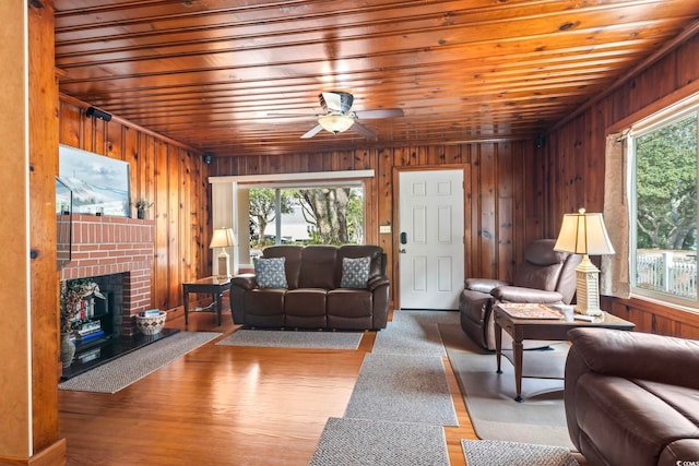 living room featuring ceiling fan, wooden walls, a fireplace, wood finished floors, and wood ceiling