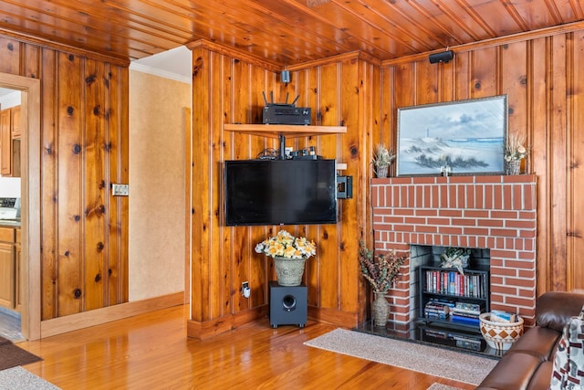 living area with a brick fireplace, wood finished floors, wood ceiling, and wooden walls