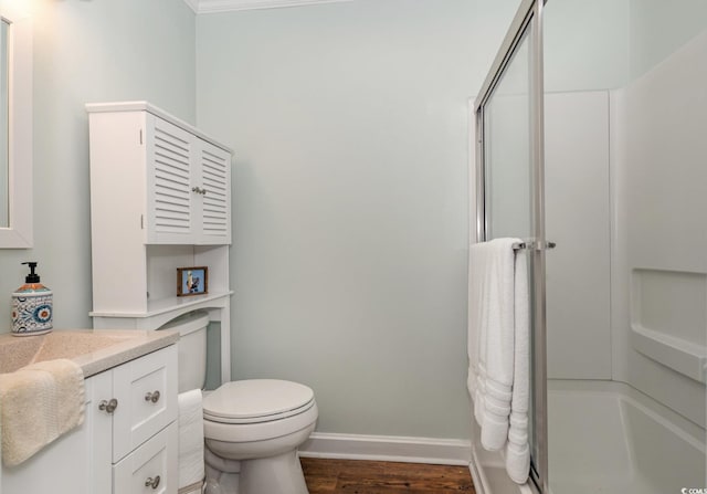 full bath with toilet, a shower stall, vanity, wood finished floors, and baseboards