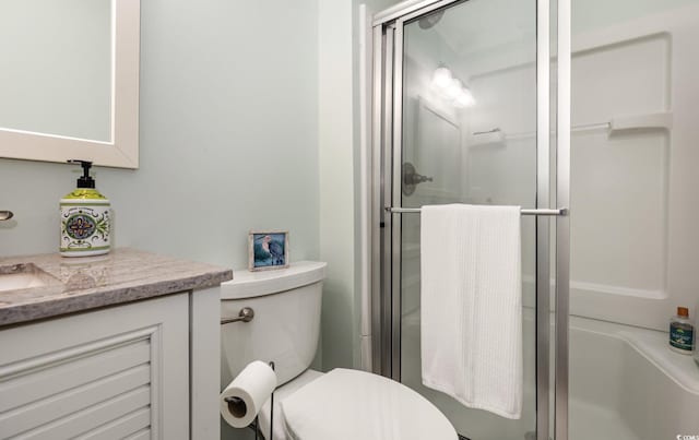 bathroom featuring a shower stall, toilet, and vanity