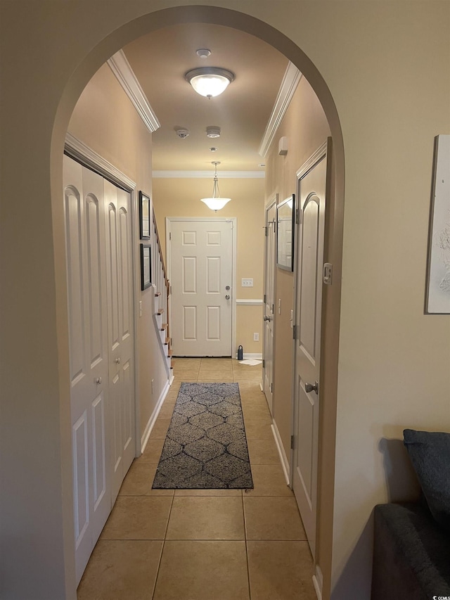 doorway to outside featuring light tile patterned floors, baseboards, arched walkways, stairway, and ornamental molding