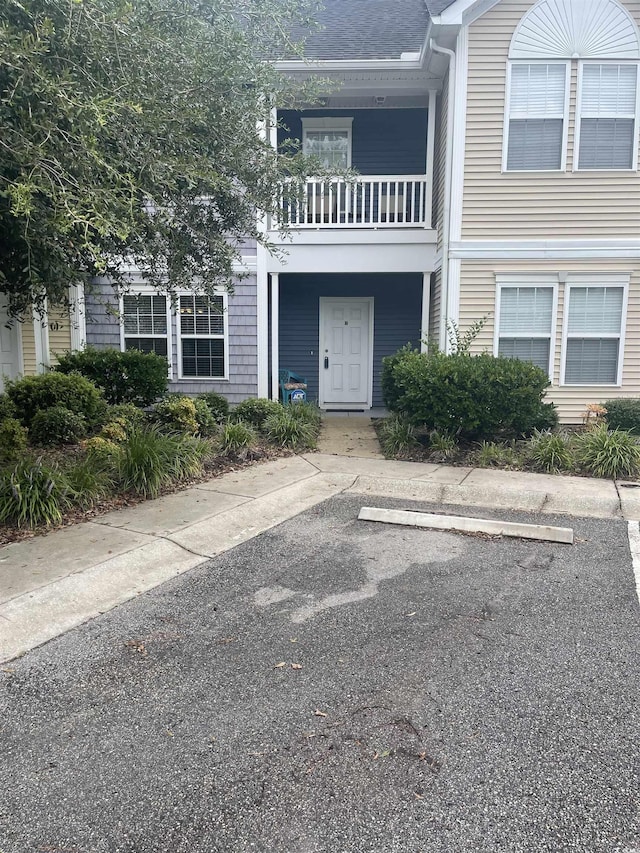 view of front of house featuring uncovered parking and a balcony