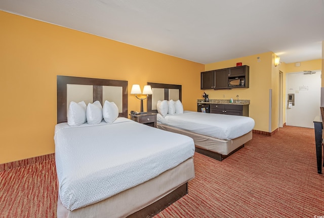 bedroom featuring indoor wet bar, carpet flooring, and baseboards