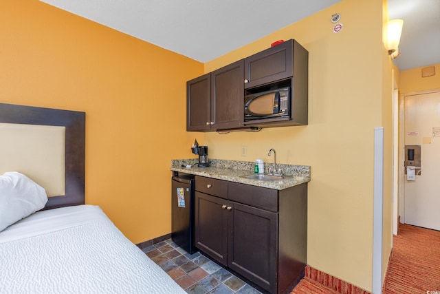 kitchen with light countertops, a sink, dark brown cabinetry, black microwave, and baseboards