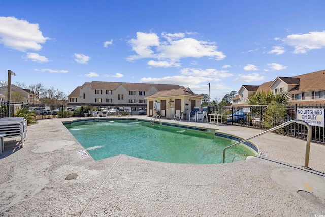 pool with a patio, fence, and a residential view