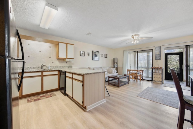 kitchen with light wood-style flooring, a peninsula, a sink, visible vents, and black appliances