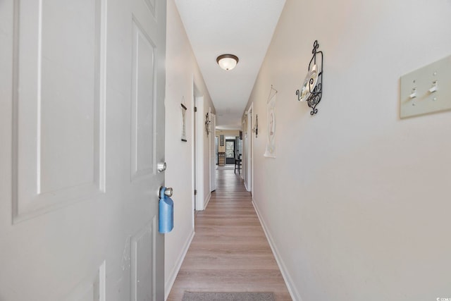 hallway featuring light wood-type flooring and baseboards