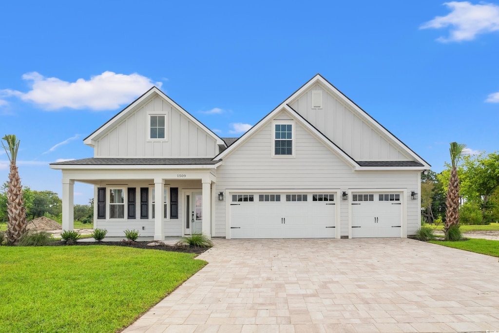 modern farmhouse style home featuring a porch, roof with shingles, decorative driveway, board and batten siding, and a front yard