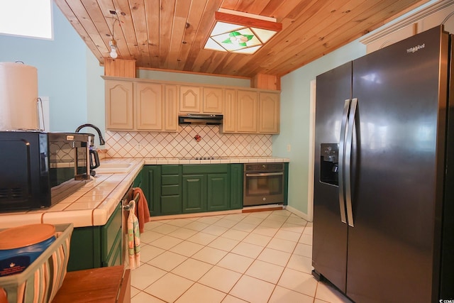 kitchen with black appliances, under cabinet range hood, a sink, tasteful backsplash, and tile countertops