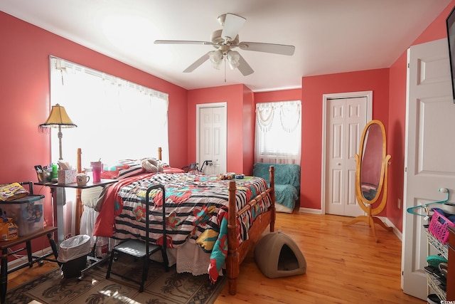 bedroom with ceiling fan, baseboards, multiple closets, and wood finished floors