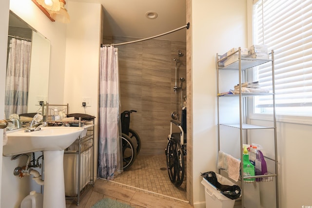 bathroom featuring a sink, tiled shower, and tile patterned flooring