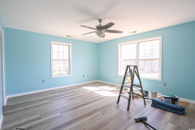 workout area featuring visible vents, a ceiling fan, baseboards, and wood finished floors