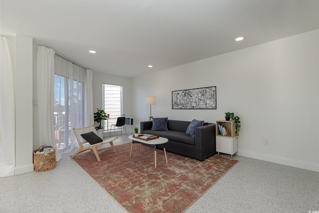 living area with baseboards, speckled floor, and recessed lighting