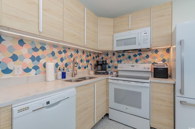 kitchen with light speckled floor, light brown cabinetry, white appliances, and a sink