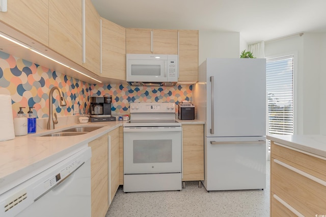 kitchen featuring light stone counters, light speckled floor, light brown cabinets, a sink, and white appliances