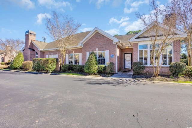 single story home with brick siding and a chimney