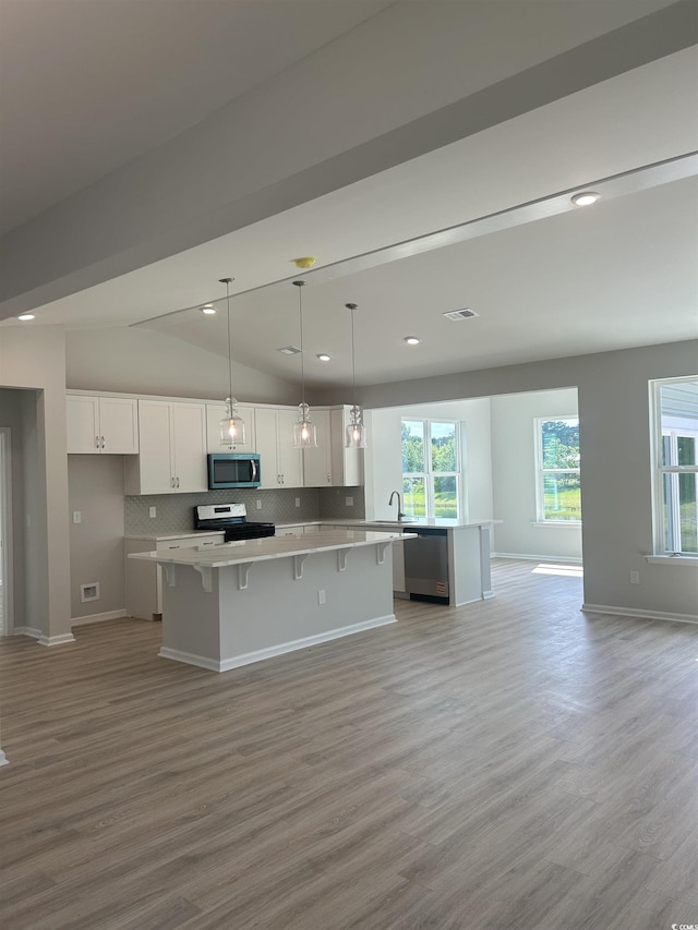 360 Kapalua Loop, Little River, SC 29566 - kitchen featuring stainless steel appliances, a kitchen island, white cabinetry, light wood-style floors, and a kitchen breakfast bar