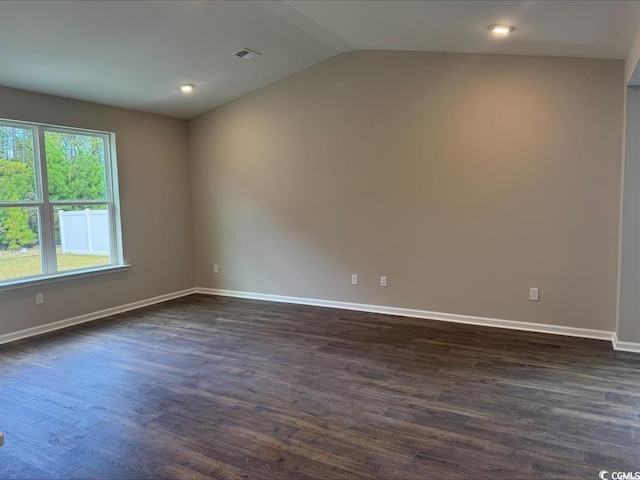 unfurnished room featuring dark wood-type flooring, baseboards, visible vents, and vaulted ceiling