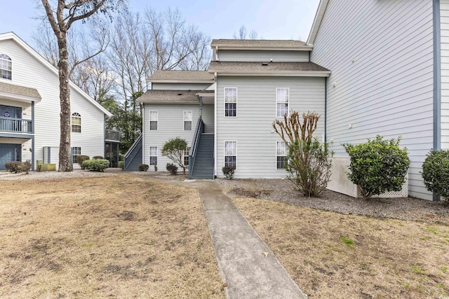 view of front of property featuring roof with shingles and stairway