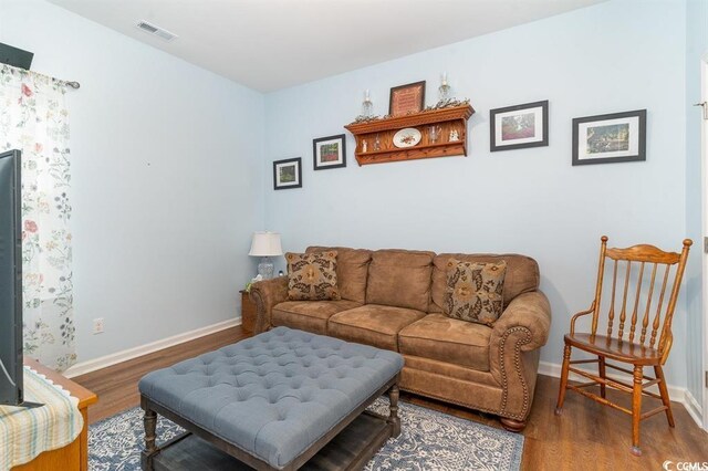 living room featuring wood finished floors, visible vents, and baseboards