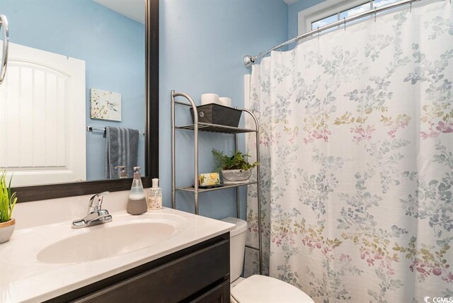 full bathroom featuring curtained shower, vanity, and toilet