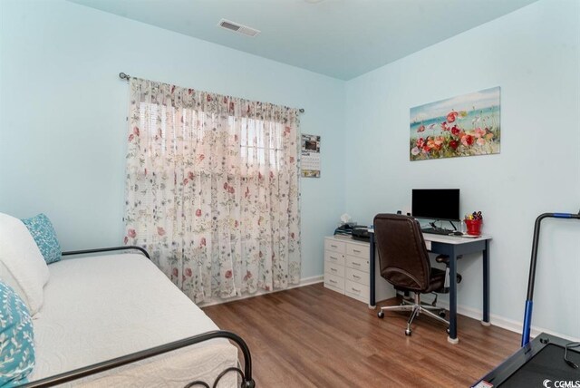 bedroom with visible vents, baseboards, and wood finished floors