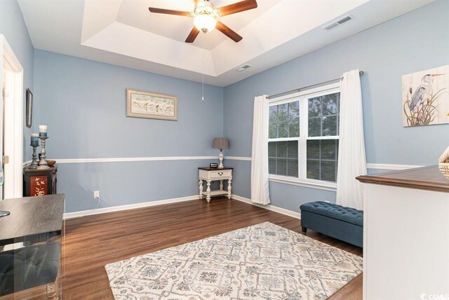 sitting room featuring wood finished floors, a ceiling fan, visible vents, baseboards, and a raised ceiling