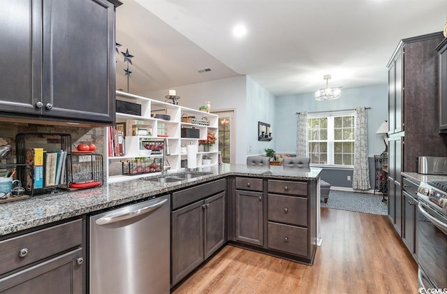 kitchen featuring stainless steel appliances, a sink, a peninsula, and dark brown cabinets