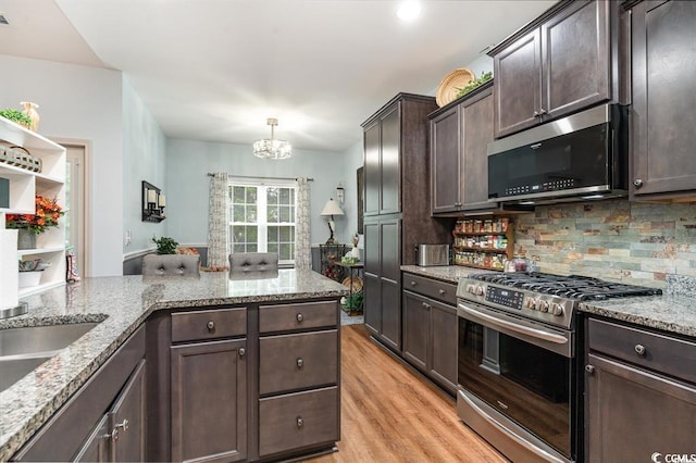 kitchen with light stone counters, light wood finished floors, backsplash, appliances with stainless steel finishes, and dark brown cabinets