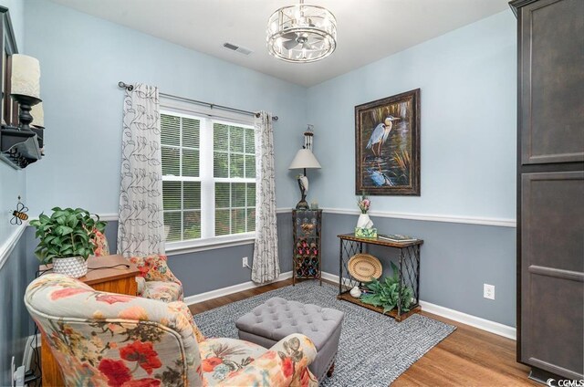 sitting room featuring baseboards, visible vents, a chandelier, and wood finished floors