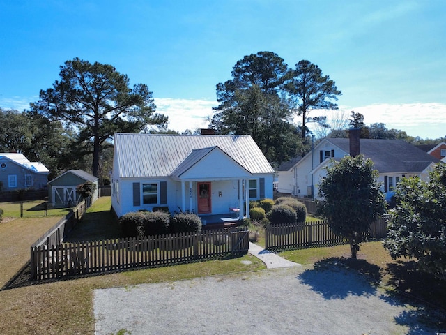 bungalow-style house with a fenced front yard, metal roof, and a front yard