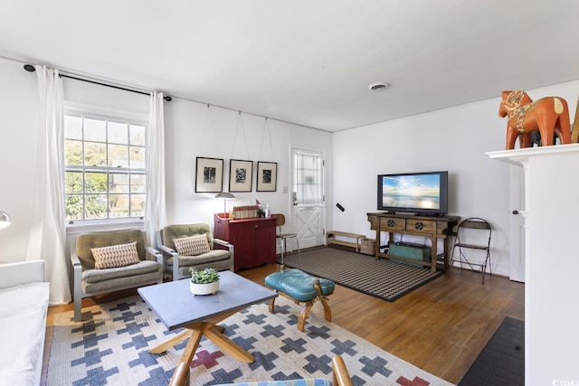 living area with wood finished floors, visible vents, and a wealth of natural light