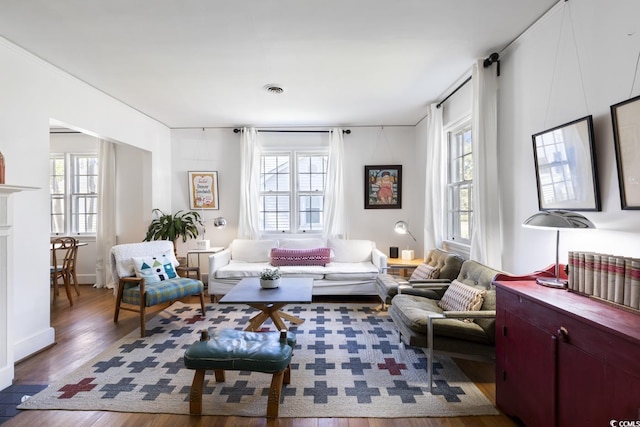 living room featuring visible vents, a fireplace, and wood finished floors