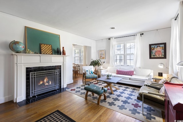 living room with a wealth of natural light, visible vents, a tile fireplace, and wood-type flooring