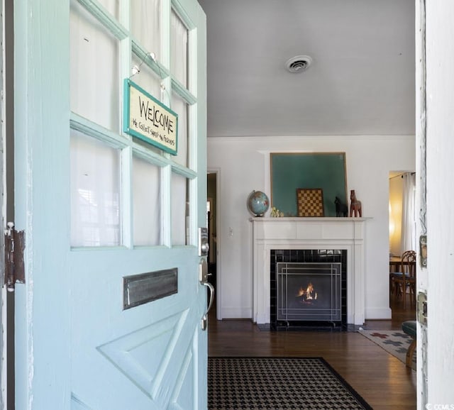 entrance foyer with visible vents, dark wood-style flooring, and a tile fireplace