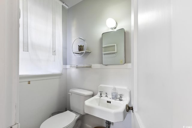 half bath featuring toilet and a sink