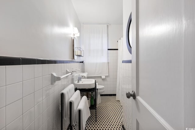 full bath featuring curtained shower, radiator, toilet, tile walls, and a sink