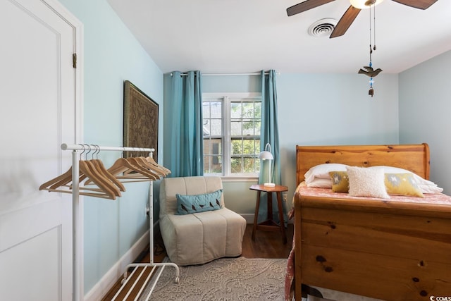 bedroom featuring baseboards, wood finished floors, visible vents, and ceiling fan