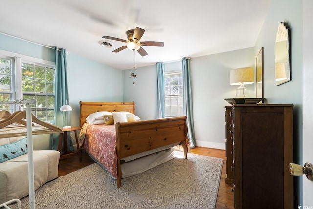 bedroom featuring visible vents, baseboards, wood finished floors, and a ceiling fan