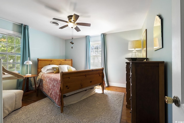 bedroom featuring multiple windows, wood finished floors, visible vents, and baseboards