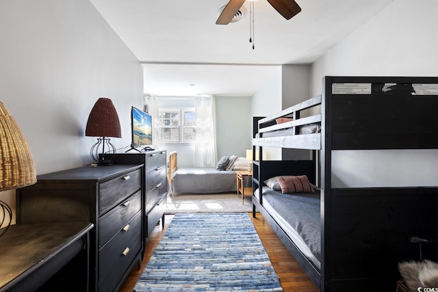 bedroom featuring ceiling fan, wood finished floors, and a fireplace