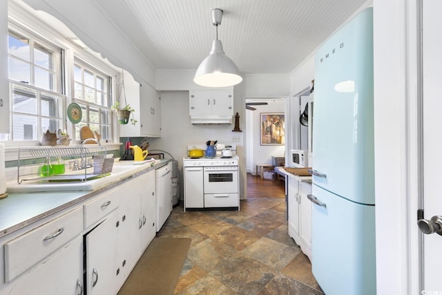 kitchen featuring stone finish flooring, under cabinet range hood, light countertops, white appliances, and white cabinetry