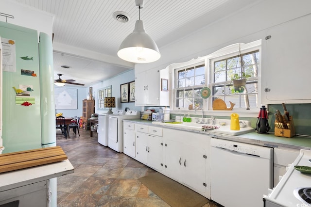 kitchen with white appliances, plenty of natural light, washing machine and dryer, and white cabinets