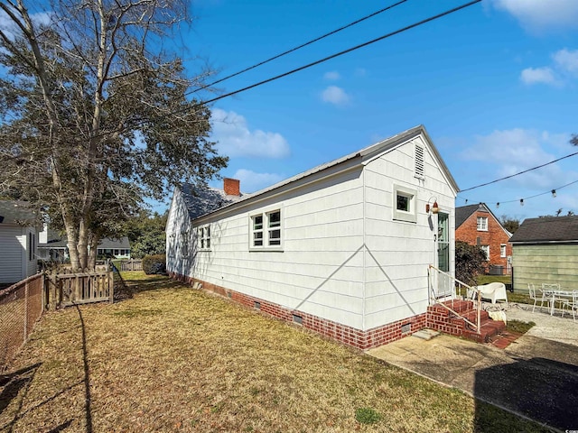 view of side of home featuring fence, entry steps, a chimney, a yard, and crawl space