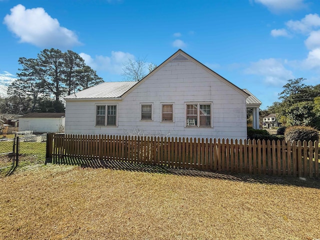 exterior space with a yard, fence, and metal roof