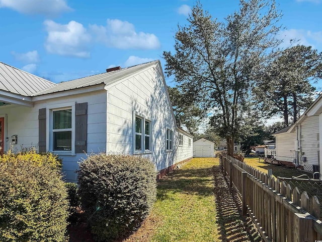 view of property exterior featuring metal roof, a yard, and fence